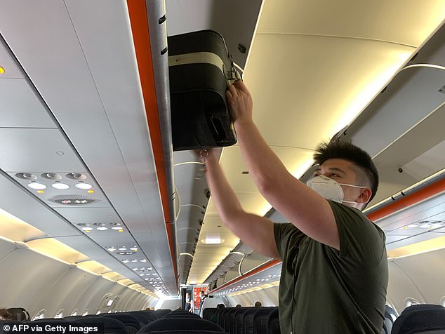 All UK arrivals – including Britons – must now fill in an online 'contact locator' form setting out where they will live for a fortnight. Refusal to do so risks a £1,000 fine. Pictured: An EasyJet passenger boards a flight while wearing a face mask