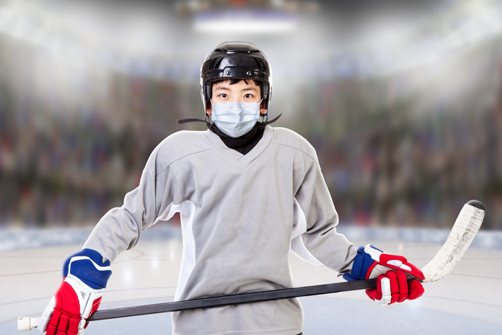 Boy suited up to play ice hockey wearing mask