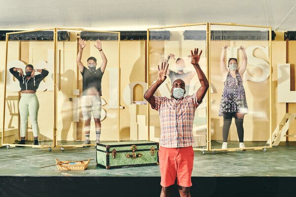 The choreographer Gerry McIntyre teaches dance steps to performers shielded behind vinyl screens to hinder the transmission of aerosols when they sing.